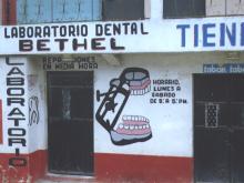 Hand-painted sign for Bethel Dental Lab with dentures graphic and operating hours.